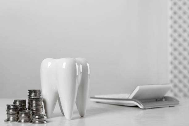 Ceramic model of tooth, coins and calculator on white table, space for text. Expensive treatment