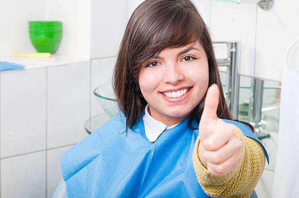 Attractive young woman thumb up in dentistry office waiting for examination