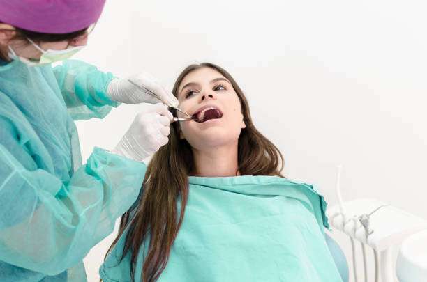 Female experienced dentist removing patients tooth. Space for text.