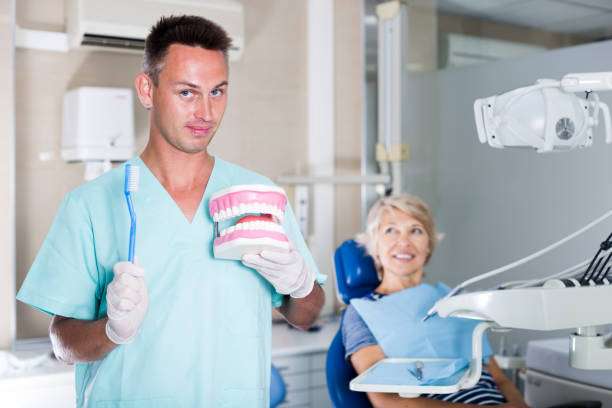 Professional dentist man explaining correct tooth brushing on dental model