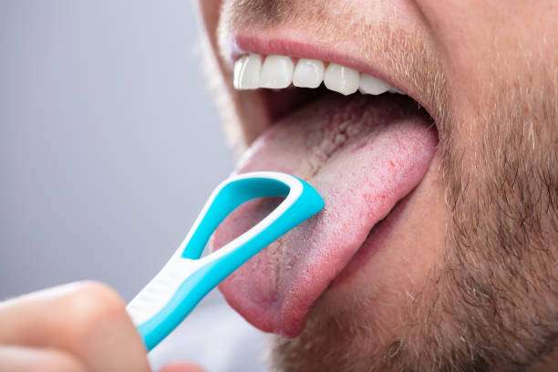 Close-up Of A Man Cleaning His Tongue With Cleaner